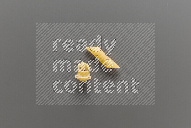 Pipe pasta with other types of pasta on grey background