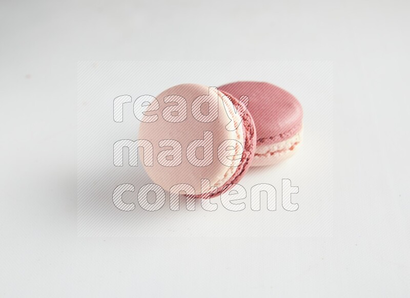 45º Shot of two Pink Litchi Raspberry macarons on white background