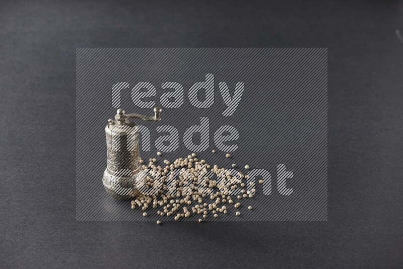 White pepper with a metal pepper grinder on black flooring