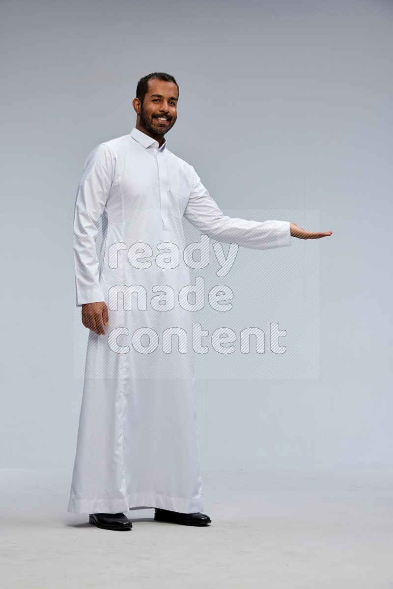 Saudi man Wearing Thob standing interacting with the camera on Gray background