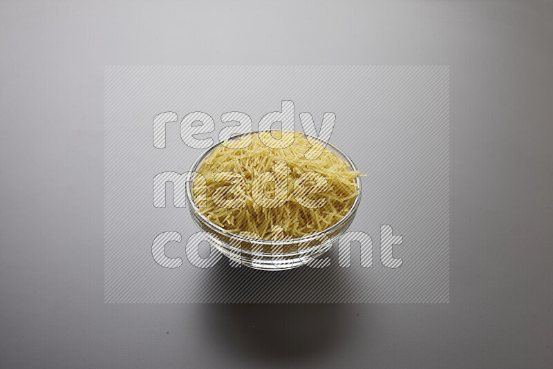 Vermicelli pasta in a glass bowl on grey background