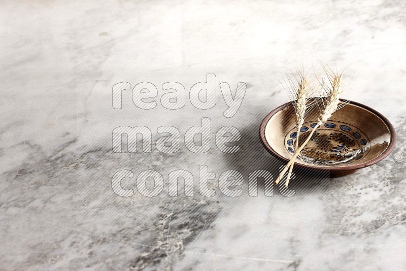 Wheat stalks on Decorative Pottery Plate on grey marble flooring, 45 degree angle