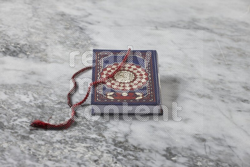 Quran with a prayer beads on grey marble background