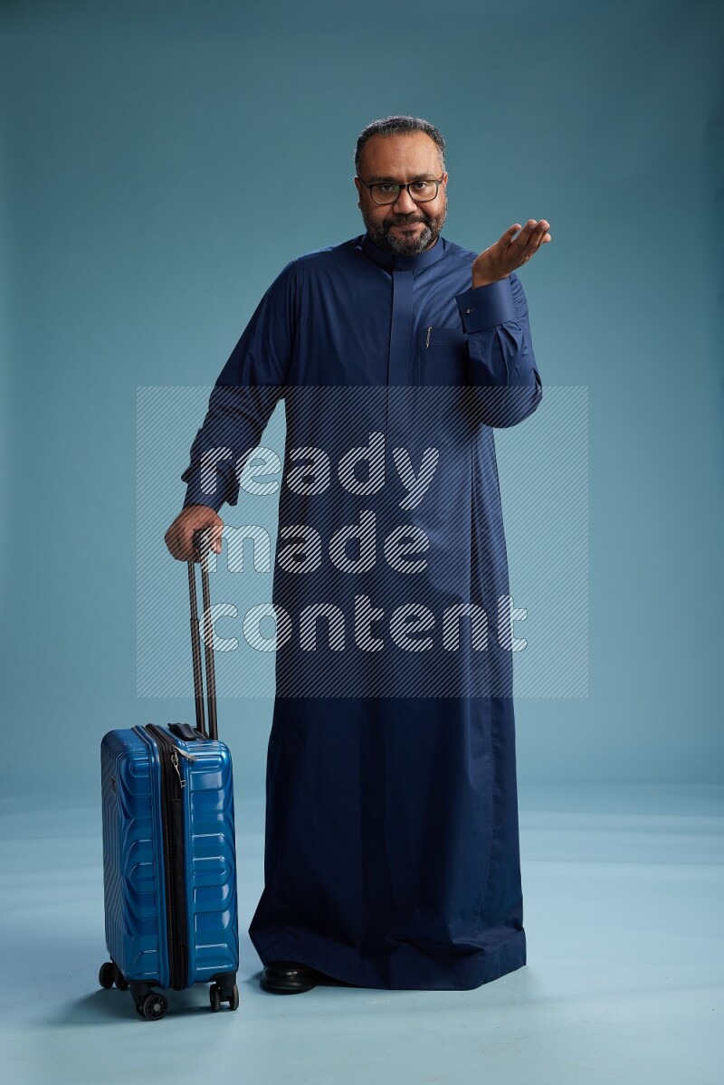 Saudi Man without shimag Standing pulling travel bag on blue background