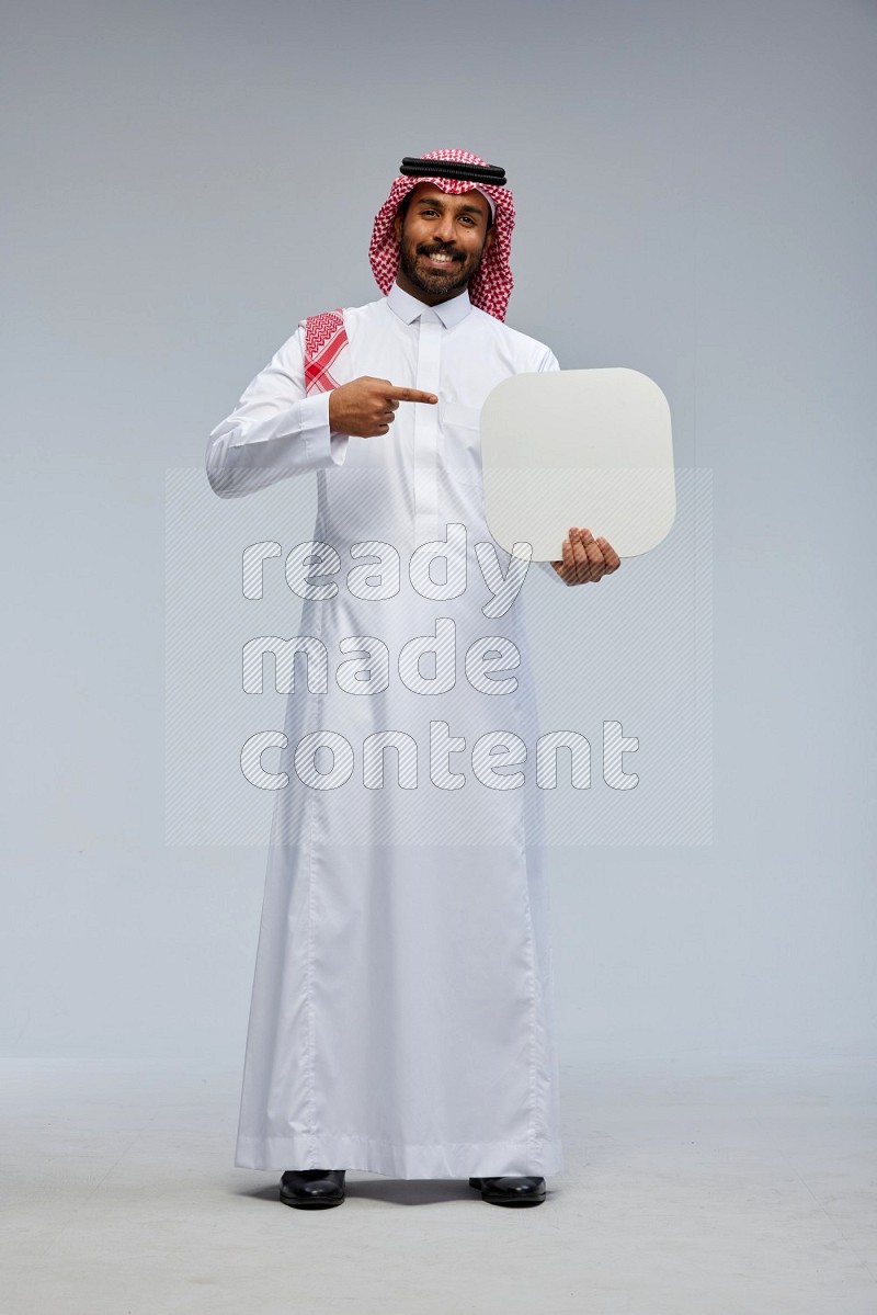 Saudi man Wearing Thob and shomag standing holding social media sign on Gray background