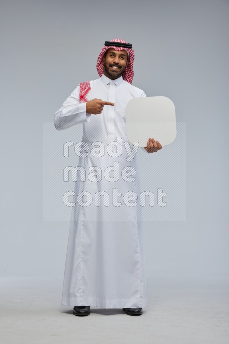 Saudi man Wearing Thob and shomag standing holding social media sign on Gray background