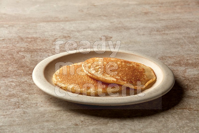 Two stacked plain pancakes in a beige plate on beige background