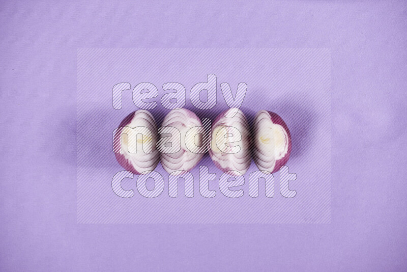 Halves red onions on a purple background