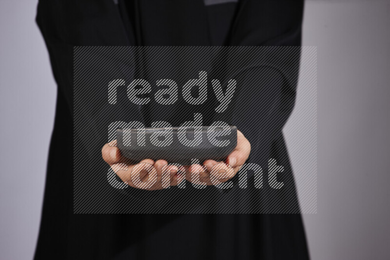 A woman in black abaya holding different pottery essentials in different positions