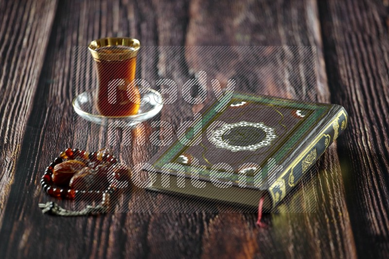 Quran with dates, prayer beads and different drinks all placed on wooden background