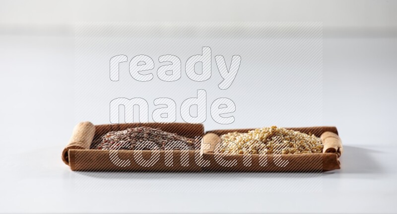 مربعان من أعواد القرفة ممتلئان ببذور الكتان وبذور السمسم علي خلفية بيضاء