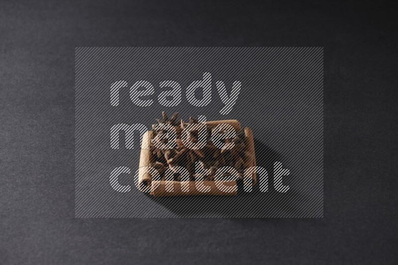 A single square of cinnamon sticks full of star anise on black flooring