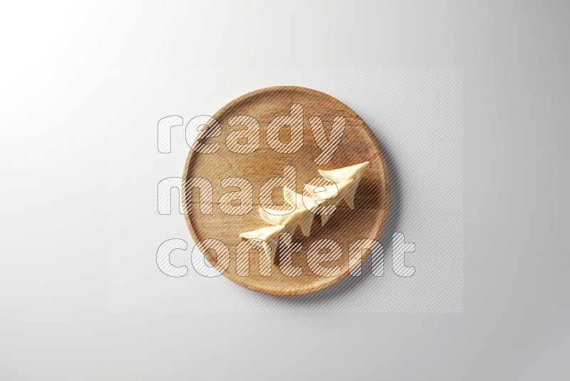 Five Sambosas on a wooden round plate on a white background