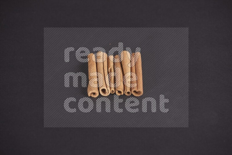 Cinnamon sticks stacked on black flooring