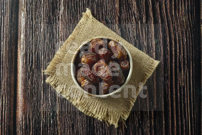 Dates in different bowls (wooden, pottery and glass) on wooden background