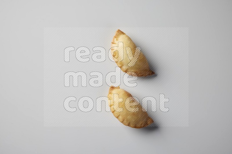 Two fried sambosa from a top angle on a white background