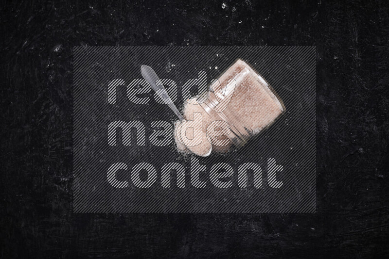 A glass jar full of fine himalayan salt on black background