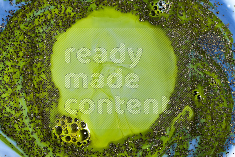 لقطة مقربة لبريق ذهبي متلألئ منتشر على خلفية من اللون الأزرق والأخضر في حركات دائرية