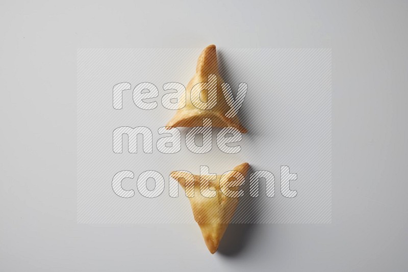 Two fried sambosa from a top angle on a white background