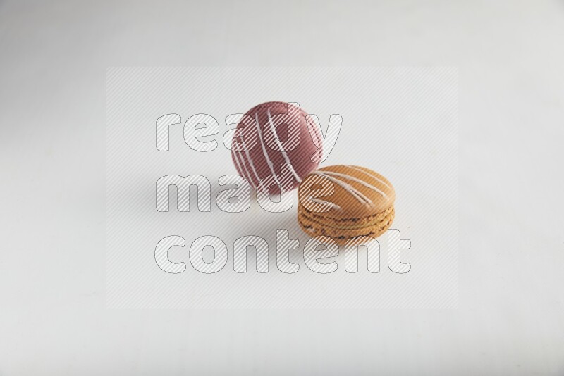 45º Shot of of two assorted Brown Irish Cream, and Red Poppy Flower macarons on white background