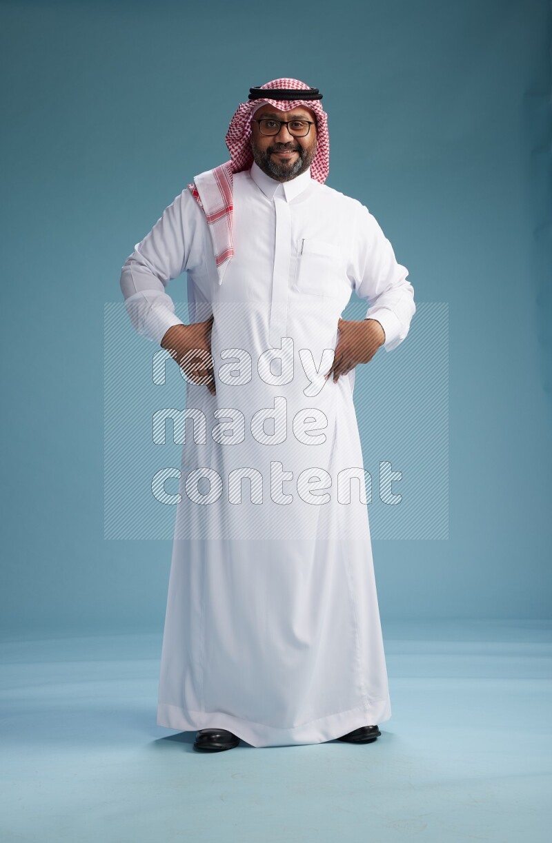 Saudi Man with shimag Standing Interacting with the camera on blue background