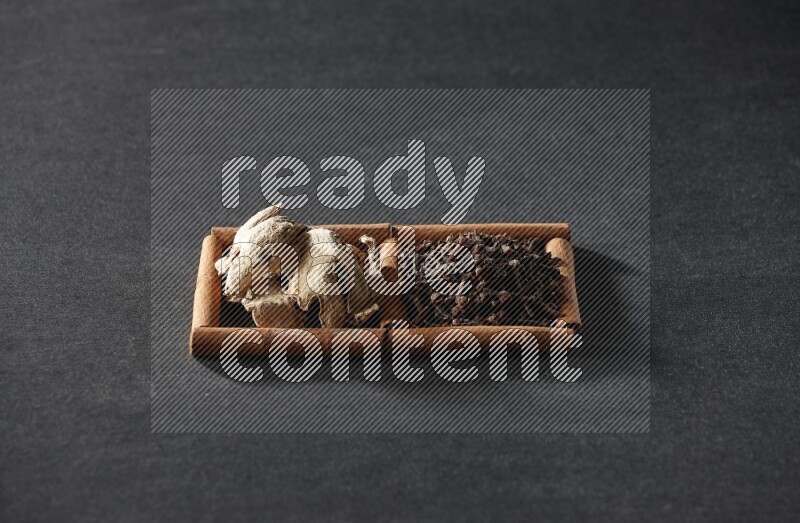 2 squares of cinnamon sticks full of cloves and dried ginger on black flooring