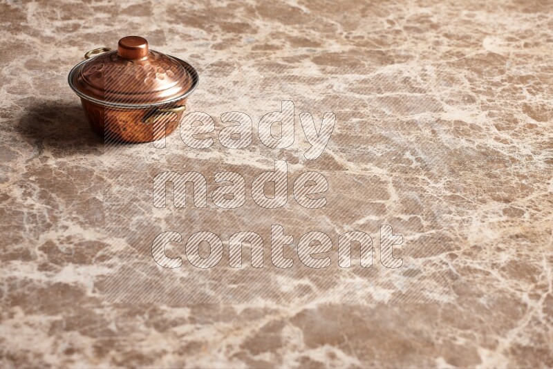 A small copper pot on beige marble background