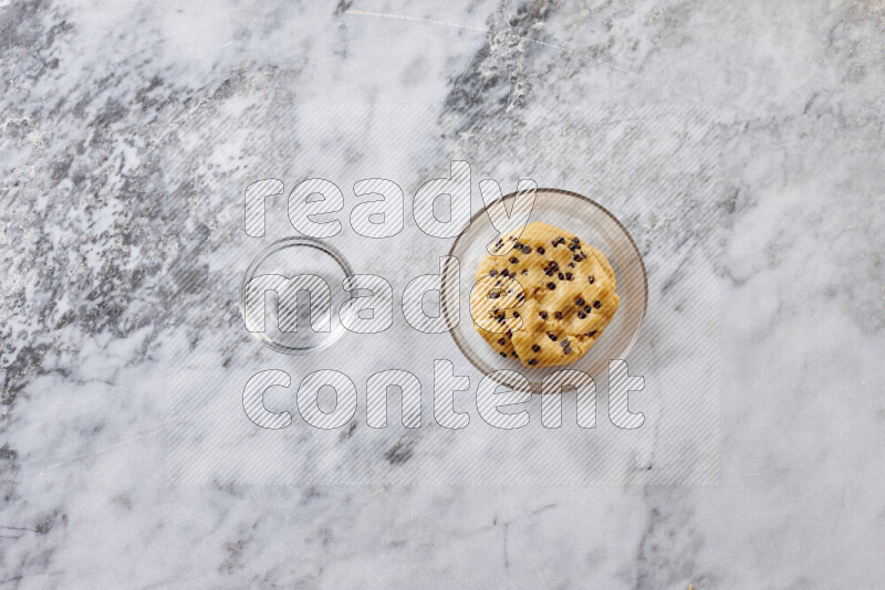 Cookies step by step with its ingredient, flour, butter, brown sugar, egg, vanilla extract, white sugar, chocolate chips and baking soda on grey marble background