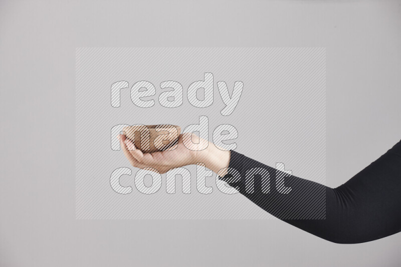 A woman in black abaya holding different wooden essentials in different positions