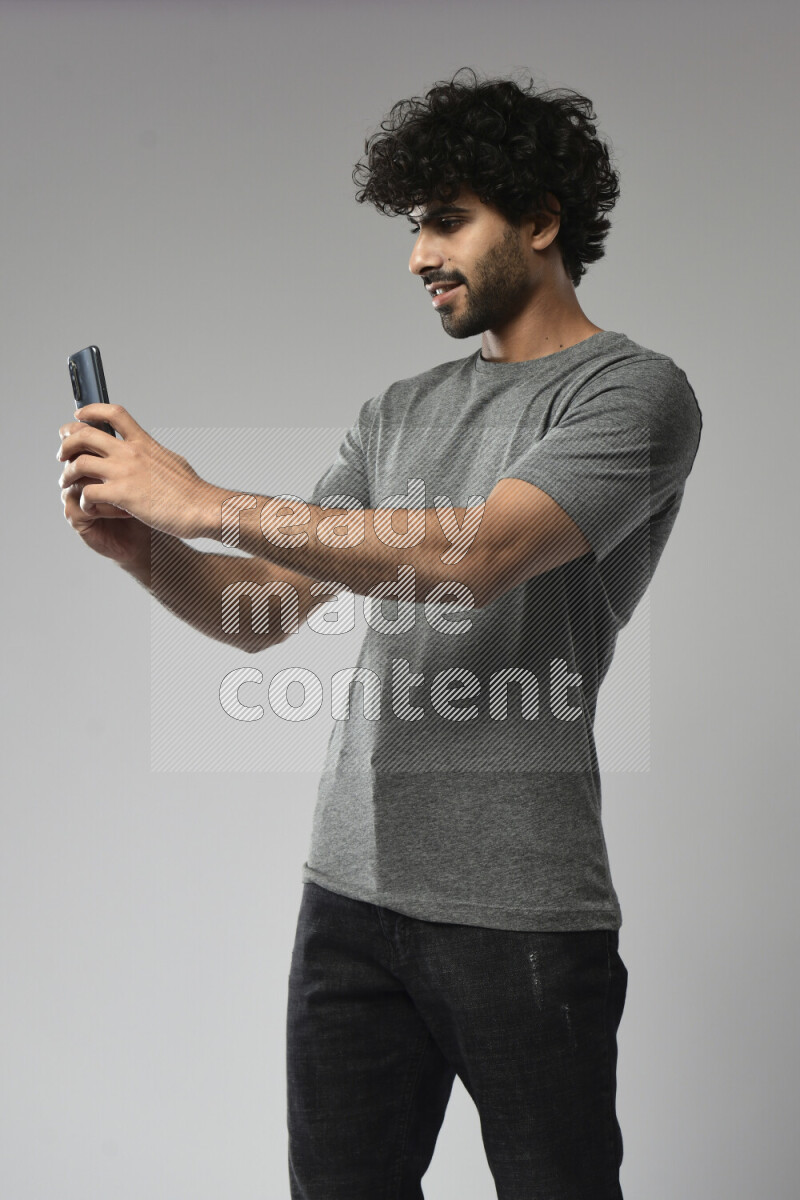A man wearing casual standing and shooting with his phone on white background