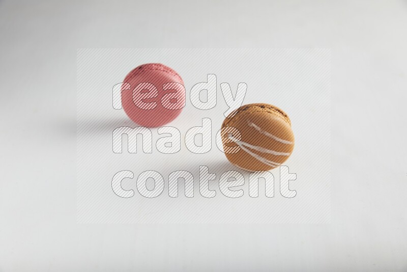 45º Shot of of two assorted Brown Irish Cream, and Pink Raspberry macarons on white background