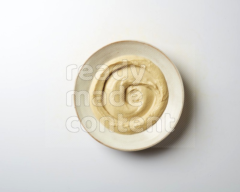 plain Hummus in a pottry plate  on a white background