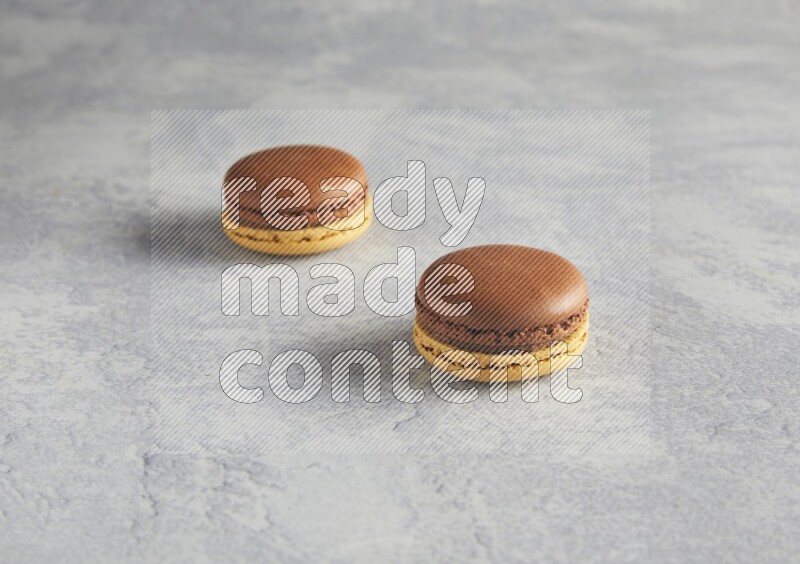 45º Shot of two Yellow and Brown Chai Latte macarons r on white  marble background
