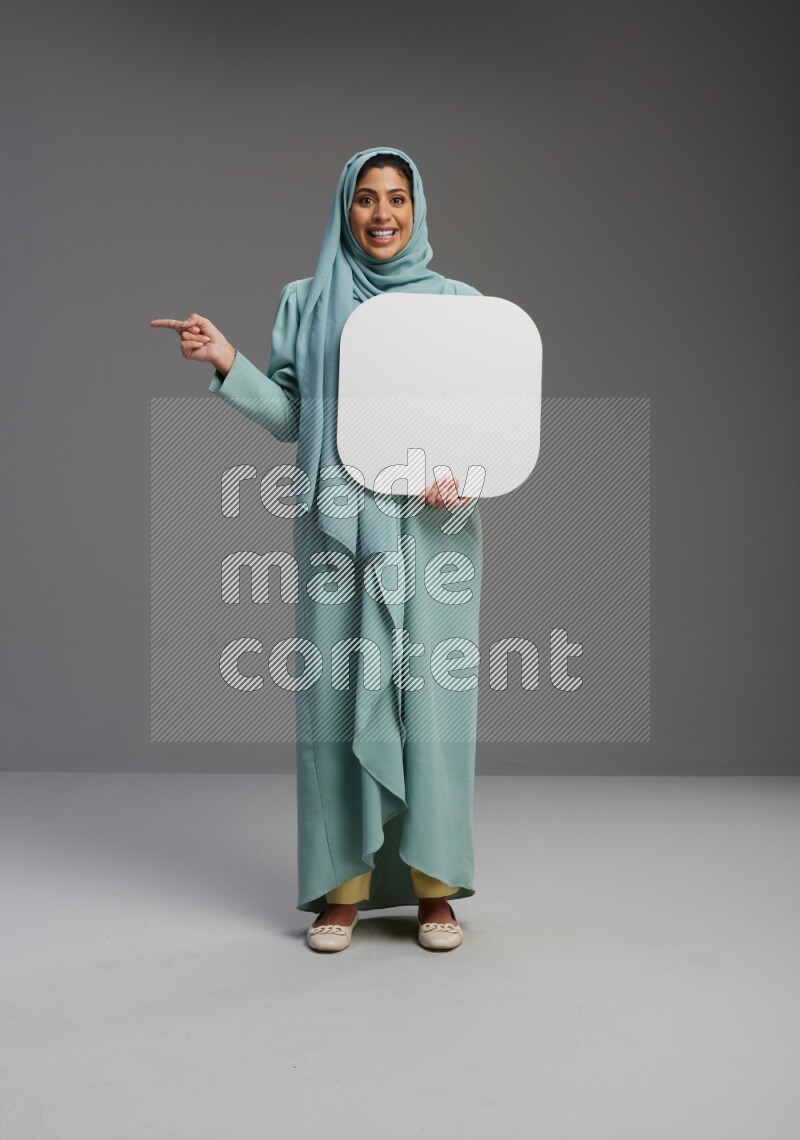 Saudi Woman wearing Abaya standing holding social media sign on Gray background