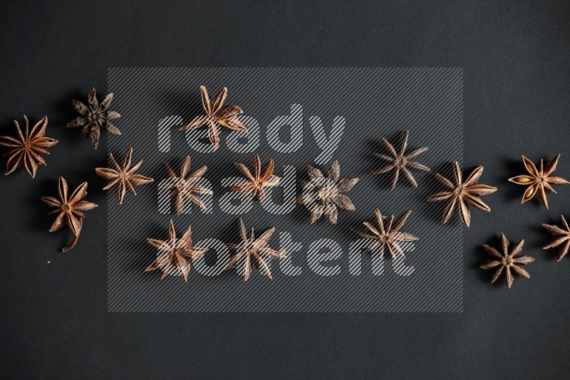 Star anise lined across the frame on black background