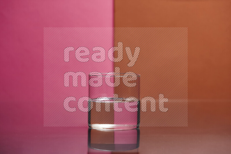 The image features a clear glassware filled with water, set against pink and dark orange background