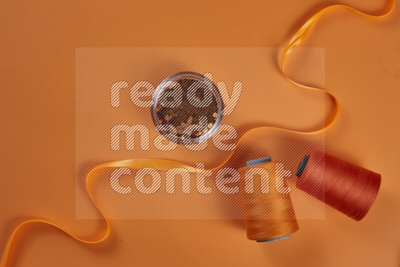 An orange collection of sewing and tailoring tools arranged on a orange background