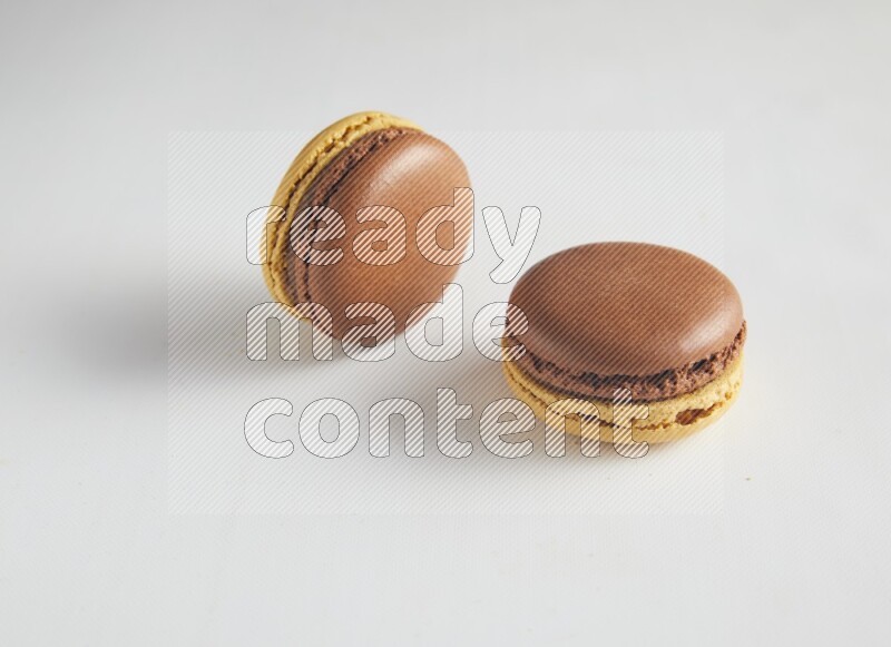 45º Shot of two Yellow and Brown Chai Latte macarons on white background