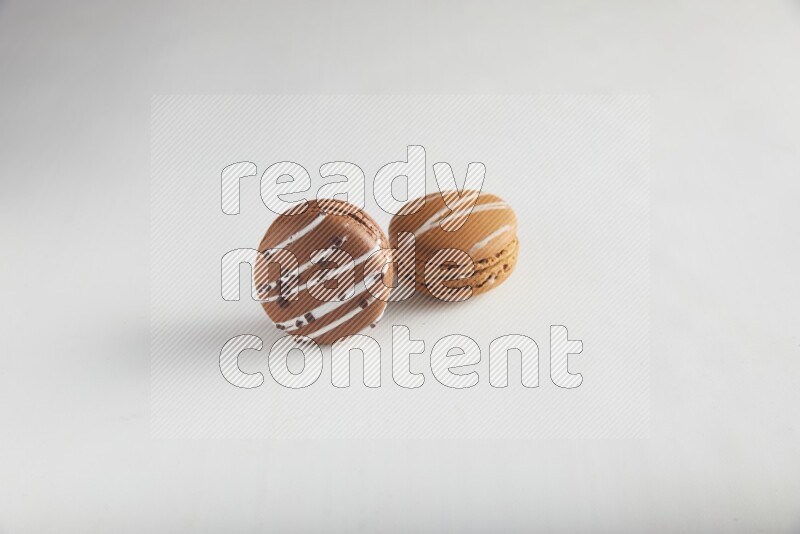 45º Shot of of two assorted Brown Irish Cream, and Brown white Chocolate Caramel macarons on white background