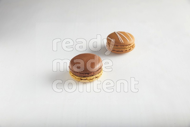 45º Shot of of two assorted Brown Irish Cream, and Yellow, and Brown Chai Latte macarons on white background