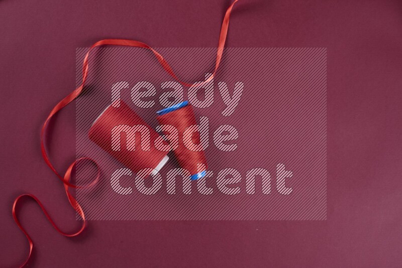 A red collection of sewing and tailoring tools arranged on a red background