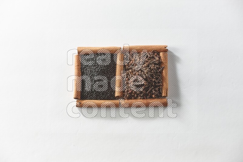 2 squares of cinnamon sticks full of cloves and black seeds on white flooring