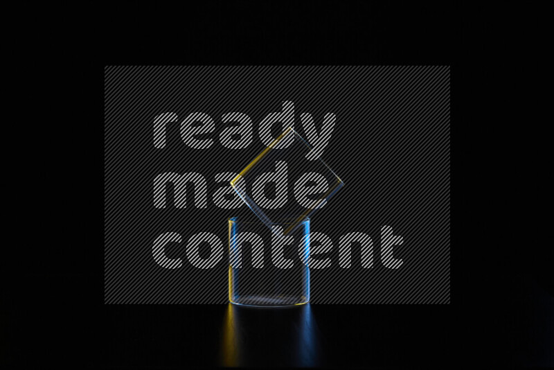 Glassware with rim light in blue and yellow against black background