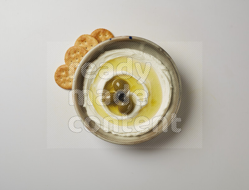 Lebnah garnished with whole olives in a grey pottery plate on a white background
