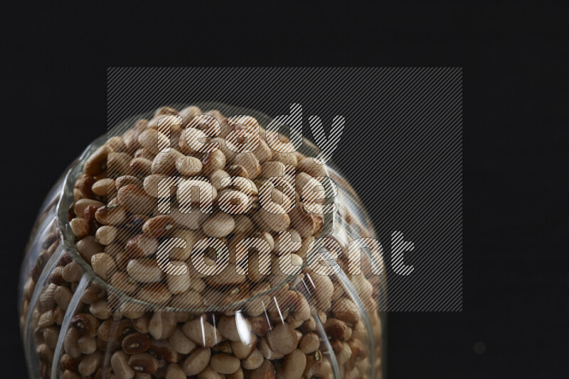 Black-eyed peas in a glass jar on black background