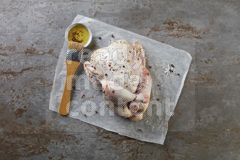 whole raw chicken on a parchment paper direct on a rustic grey background