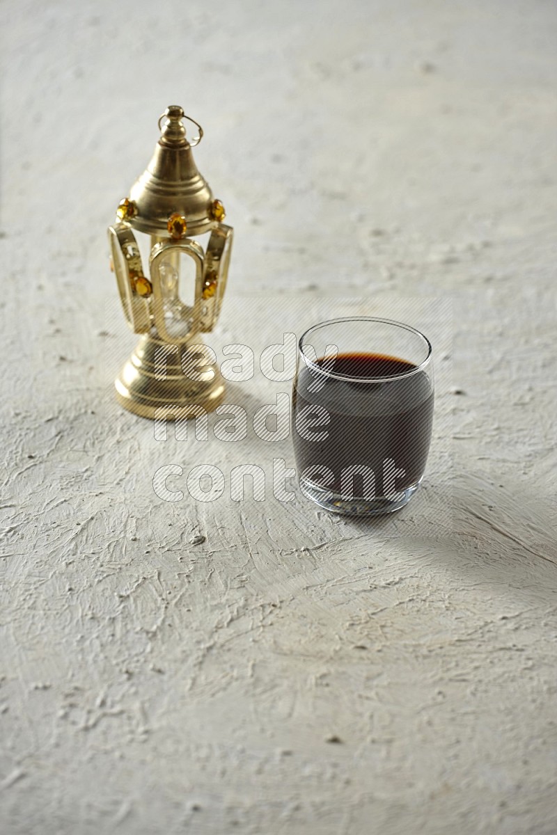 A golden lantern with different drinks, dates, nuts, prayer beads and quran on textured white background
