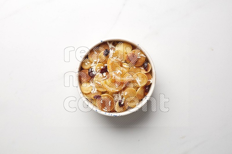 Top-view shot of orange candy cereal pancakes in a round bowl on white background