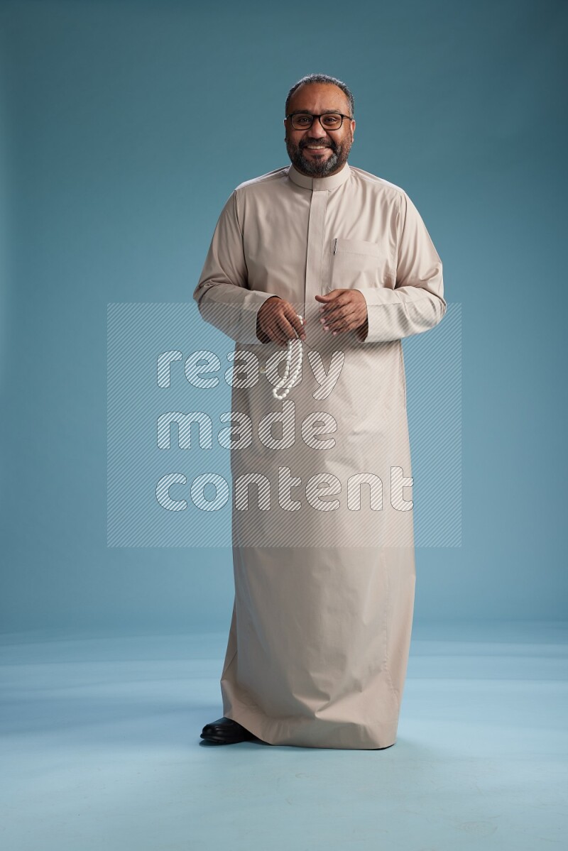 Saudi Man without shimag Standing Interacting with the camera on blue background