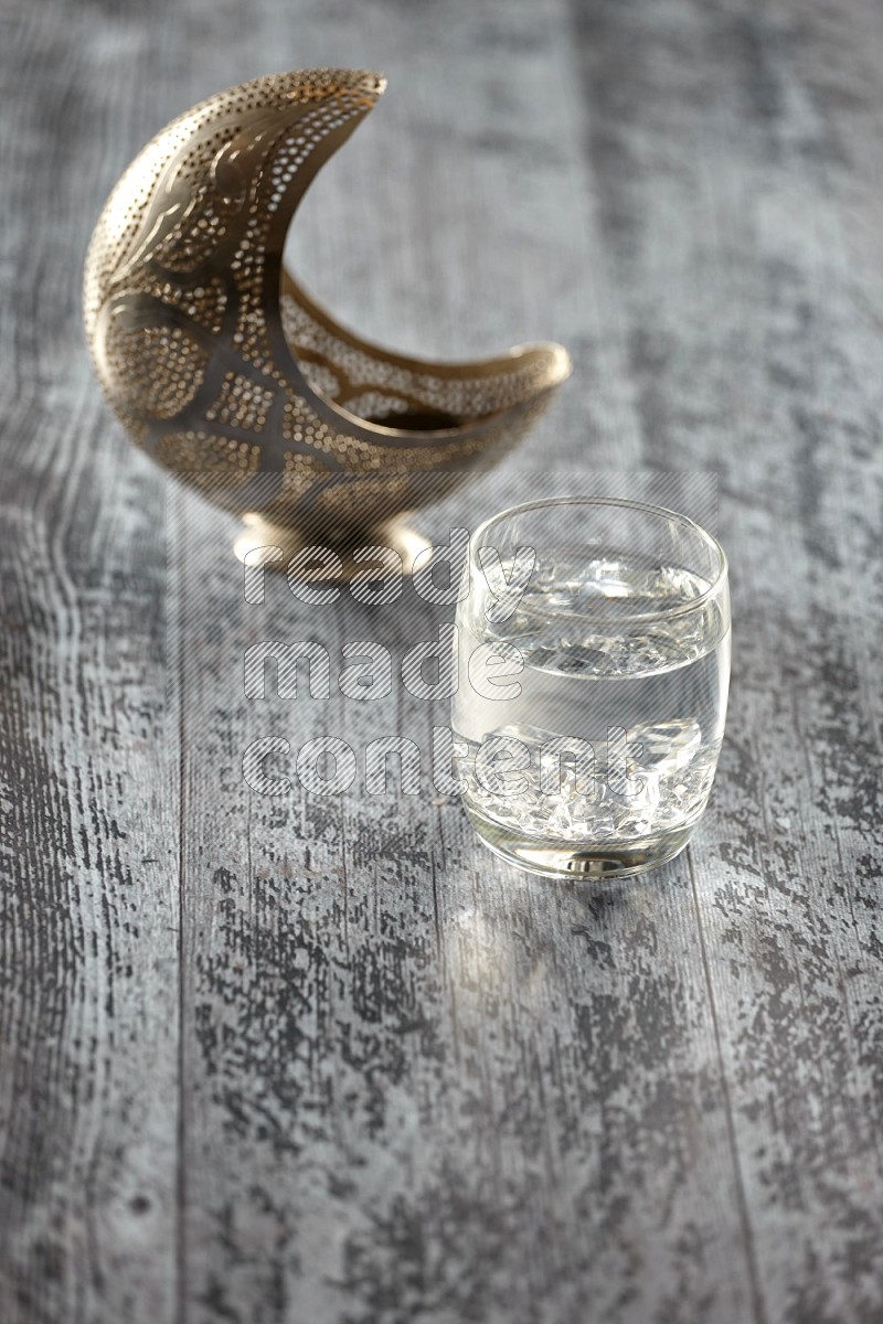 A silver lantern with drinks, dates, nuts, prayer beads and quran on grey wooden background
